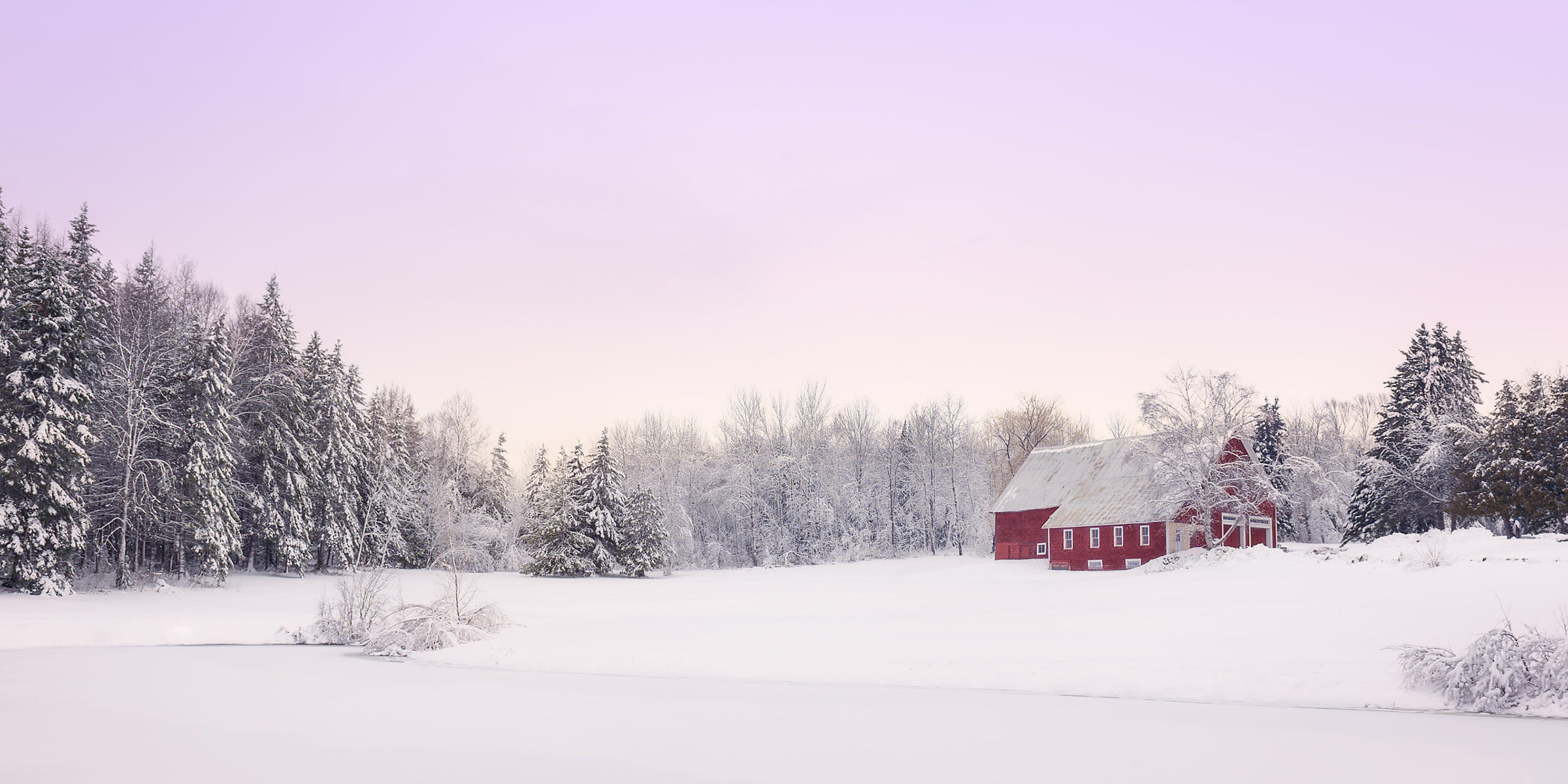 Snowy winter scene with red barn in distance
